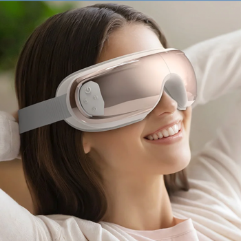 Zrelaksowana kobieta w różowo-złotym inteligentnym masażerze do oczu RENPHO Eyeris 3, widok z boku, uśmiecha się.