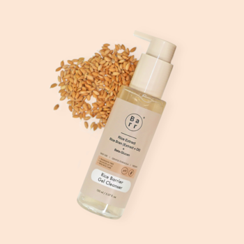 Przezroczysta butelka Rice Barrier Gel Cleanser z pompką, obok rozsypane ziarna ryżu na jasnobeżowym tle.