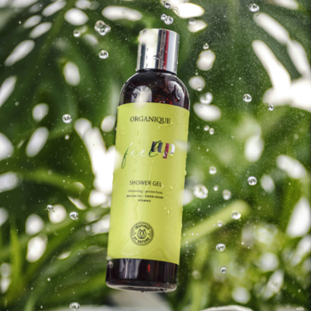 ORGANQIUE Feel Up żel pod prysznic z zieloną herbatą, butelka wśród kropel wody i liści.