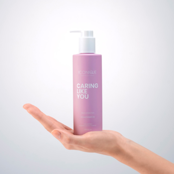 Fioletowa butelka odżywki ICONIQUE CARING LIKE YOU Hydrating z pompką, trzymana dłonią. Widok z przodu.