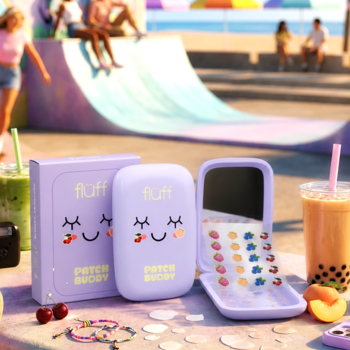 Fluff Juicy Patches: fioletowe etui z lusterkiem i kolorowymi plasterkami na niedoskonałości, na tle plaży.