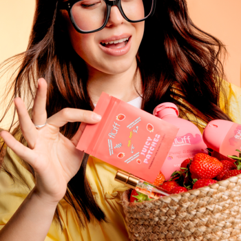 Kobieta trzyma różowe Fluff Juicy Patches Strawberry Vibe obok koszyka truskawek i kosmetyków.