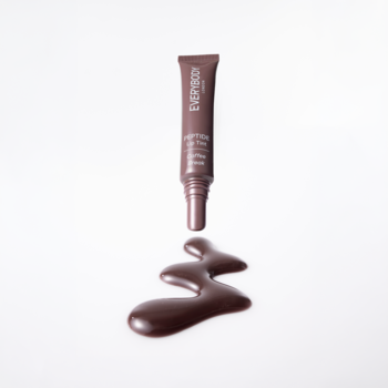Brązowo-mauve tint do ust Coffee Break Everybody, tubka i wylany płyn z peptydami na białym tle.