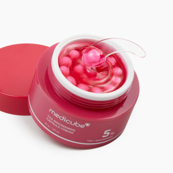 Medicube TXA Niacinamide Capsule Cream: otwarty różowy słoik z widocznymi różowymi kapsułkami i łyżeczką na białym tle.