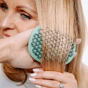 Profesjonalna szczotka Manta Flexguard miętowa, używana przez kobietę do delikatnego rozczesywania blond włosów.