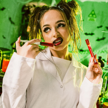 Kobieta w labie z błyszczykiem Fluff Beauty Lab Bloody Gloss w krwistej czerwieni, ze strzykawką; Halloween vibe.