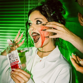 Kobieta z halloweenowym makijażem i czerwoną "krwią" na twarzy, trzyma maskę Fluff Jelly Infusion. Zielone tło.