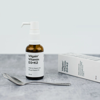 Vilgain Witamina D3+K2 w kroplach 30 ml, brązowa butelka z białym dozownikiem, obok łyżeczka i pudełko.
