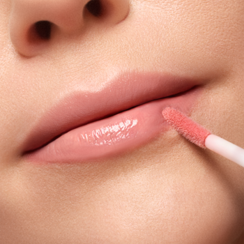Zbliżenie: Artdeco Plumping Lip Fluid Glossy Nude aplikowany aplikatorem na lśniące, pełne usta.