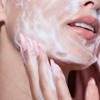 Kobieta aplikująca nawilżającą piankę Swederm Face Cleanser na twarz, dłonie masują skórę z białą pianą.