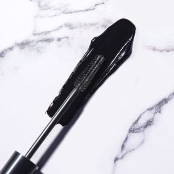 ARTDECO Gorgeous Volume Mascara: zbliżenie na czarny tusz o kremowej konsystencji na aplikatorze i marmurze.