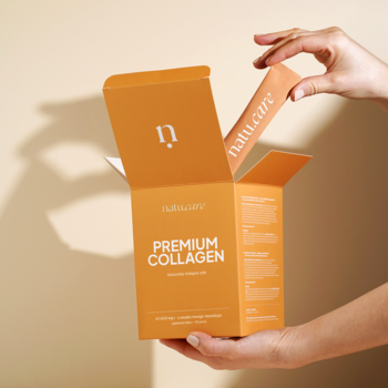 Dłoń wyjmuje pomarańczową saszetkę Natu.Care Premium Collagen mango-marakuja z otwartego pudełka.