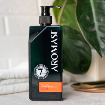 Czarna butelka szamponu AROMASE Dry Scalp Soothing Shampoo z pompką, widok z przodu, na białych ręcznikach.