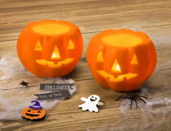 Zbliżenie na dwie świecące dynie lampiony Halloween, z pajęczyną, pająkami i duchem na drewnianym tle.