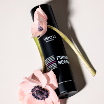 Czarny pojemnik Veoli Botanica FIRMING SECRET, senolitycznej maski ujędrniającej, z różowymi kwiatami.