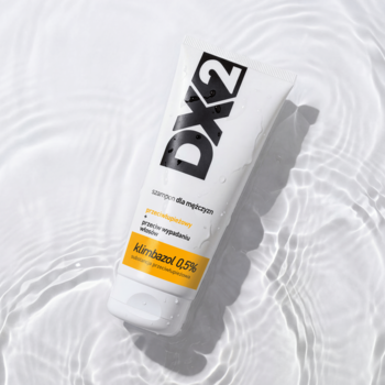 Biała tuba szamponu DX2 przeciwłupieżowego dla mężczyzn z Klimbazolem, leżąca na falującej wodzie.