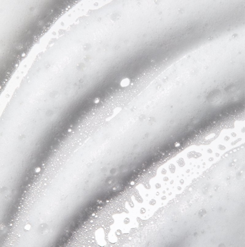 Zbliżenie na białą, spienioną teksturę odżywki Miraculous Recovery z ceramidami, widoczne smugi i bąbelki.