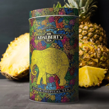 Adalbert's Tea Tropical Black Tea, cylindryczna puszka z barwnym wzorem, złotym słoniem, świeże ananasy.