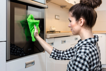 Kobieta wyciera piekarnik zieloną ściereczką Vileda Microfibre Colors, efektywne sprzątanie bez chemii.