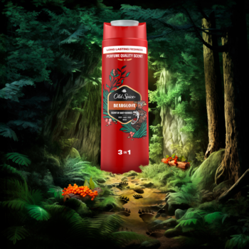Czerwony żel pod prysznic Old Spice Bearglove 3-in-1, butelka z zielonymi liśćmi, na tle leśnej ścieżki.