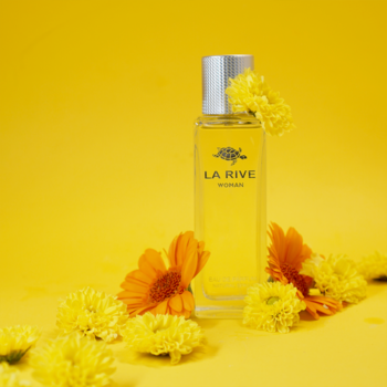 La Rive perfumy w smukłej szklanej butelce, z żółtym płynem, otoczone żółto-pomarańczowymi kwiatami na żółtym tle.