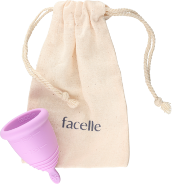 Kubeczek menstruacyjny Facelle S, fioletowy silikonowy, z beżowym woreczkiem, widok z przodu na jasnym tle.