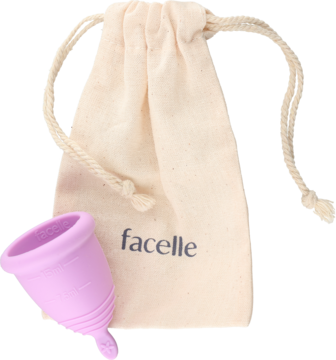 Kubeczek menstruacyjny Facelle S, fioletowy silikonowy, z beżowym woreczkiem, widok z przodu na jasnym tle.