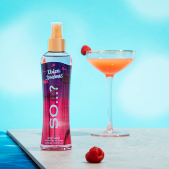 Mgiełka do ciała So...? Escapes Ibiza Dreams, butelka z tropikalnym wzorem, obok różowy drink i maliny na tle błękitnego nieba.