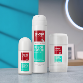 Trzy białe antyperspiranty Hidrofugal Dusch-Frische: roll-on, spray i sztyft, dla świeżości prysznica, na tle łazienki.