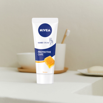 NIVEA Krem do rąk Protective Care w białej tubce z niebieskim logo i pomarańczowym wzorem miodu, widok z przodu.