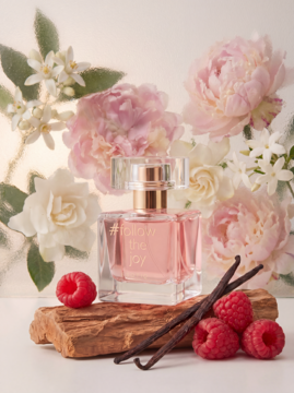 Esotiq #follow the joy woda perfumowana, różowa butelka z malinami, wanilią i kwiatami na drewnianej podstawce.