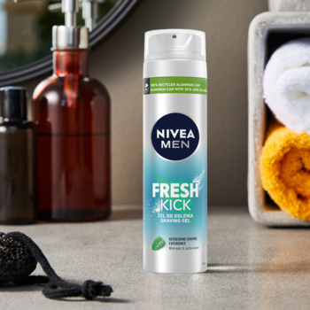 NIVEA MEN Fresh Kick żel do golenia z miętą, biało-niebieska butelka, widok z przodu na tle łazienki.