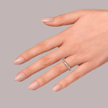 Dłoń z eleganckim manicure nude wykonanym bazą Semilac Be Beautiful Base Nude. Owalne paznokcie, pierścionek.