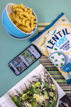 Paczka OhOh! Lentil Chips śmietankowo-cebulowych z chipsami w misce, telefonem i magazynem. Widok z góry.