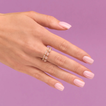 Zadbane dłonie z półtransparentnym lakierem Natural Rose do French. Na palcu złote pierścionki z różowymi kamieniami.