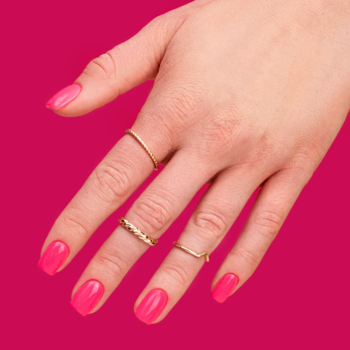 HEMA-free lakier hybrydowy Friendly Magenta: dłoń z błyszczącymi, intensywnie różowymi paznokciami i złotymi pierścionkami.