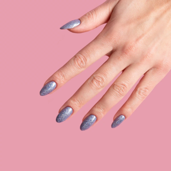 Dłoń z długimi owalnymi paznokciami, pokrytymi fioletowo-niebieskim lakierem FLASH z multikolorową drobiną na różowym tle.