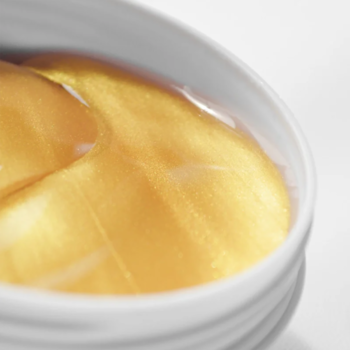 Zbliżenie złotych hydrożelowych płatków Love Skin Golden Snail ze śluzem ślimaka, w białym słoiczku.