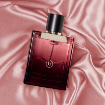 Bugatti Bella Donna Intensa, ciemnoróżowy flakon perfum z czarną nakrętką na pofałdowanym różowym atłasie.