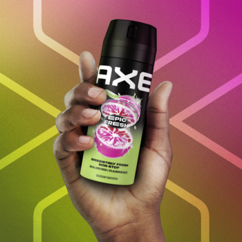 Dezodorant w sprayu AXE Epic Fresh zielony z owocami, trzymany w dłoni na rozmyto-kolorowym tle.