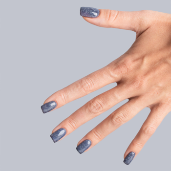 Dłoń z kwadratowymi paznokciami, głęboki niebiesko-szary lakier Classy&Sassy z drobinkami. Widok z góry.