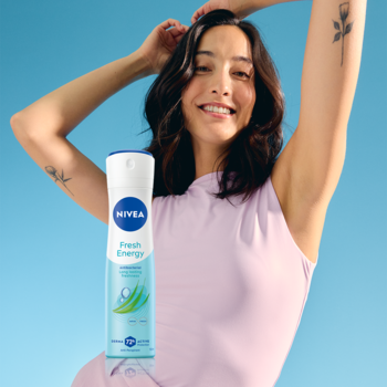 NIVEA Fresh Energy antyperspirant w sprayu 72h z trawą cytrynową, radosna kobieta z uniesionymi rękami, niebieskie tło.