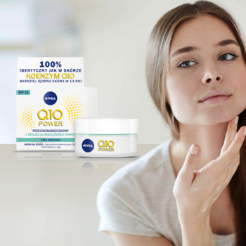 Biały krem NIVEA Q10 Power z logo Q10 i kartonik. Kobieta w tle. Wygładza zmarszczki, SPF15.