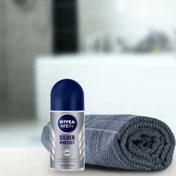 NIVEA MEN Silver Protect antyperspirant w kulce, niebieska nakrętka, obok szary ręcznik, na blacie.