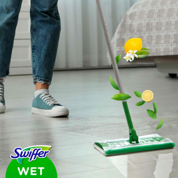 Zielony mop Swiffer Wet czyści jasną podłogę, z latającymi cytrynami i liśćmi symbolizującymi świeży zapach.