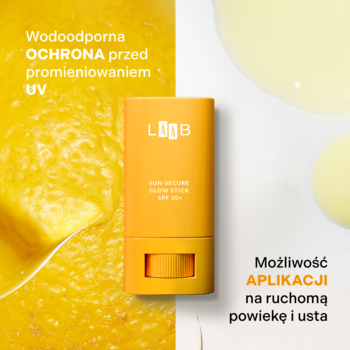 Pomarańczowy sztyft przeciwsłoneczny AA LAAB Sun-Secure Glow Stick SPF 50+ na tle cytryny i kropli oleju.