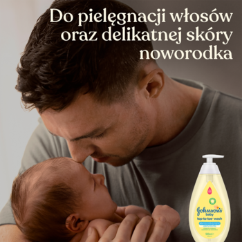 Zbliżenie na ojca całującego noworodka, obok żółty płyn Johnson’s Baby do mycia ciała i włosów.