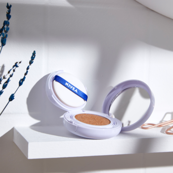 NIVEA Cellular Care Cushion 3w1 SPF 15 otwarty. Fioletowe opakowanie z lustrem, podkładem i gąbeczką na białej półce.