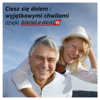 Uśmiechnięta para cieszy się życiem dzięki blend-a-dent, klejowi do protez. On niesie ją na plecach, tło: niebo.