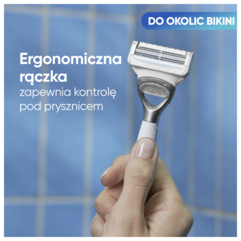 Ręka trzyma biało-srebrną maszynkę Gillette Venus Satin Care dla kobiet, z ergonomiczną rączką, na niebieskim tle. Do bikini.